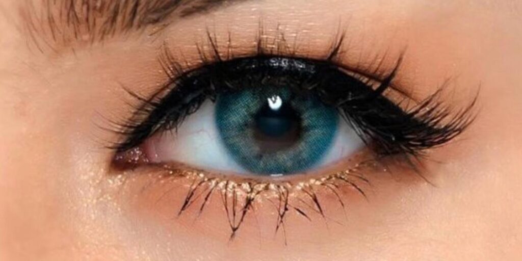 Kitty Kawaii Ava Blue monthly colored contacts on dark eyes showing deep peacock teal with seamless no-ring finish for natural blended look
