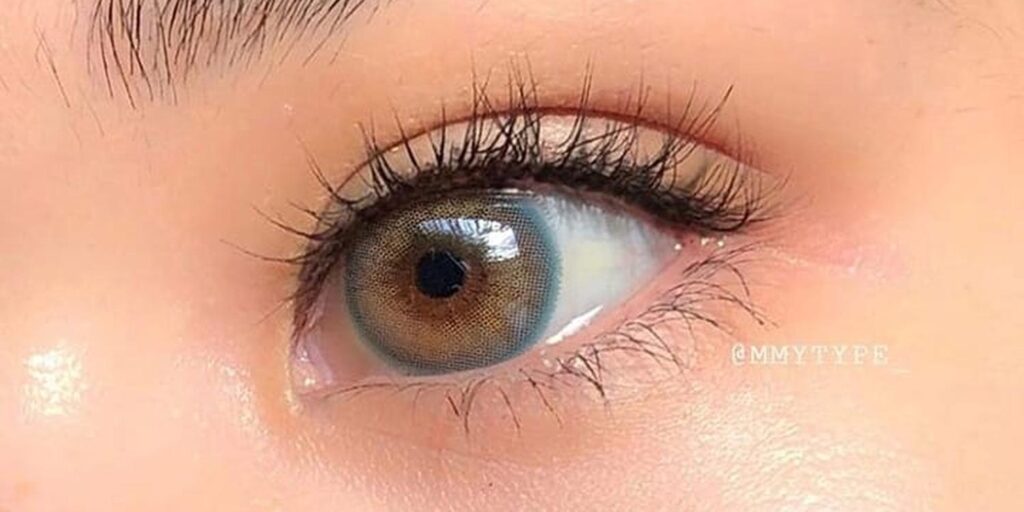 Sisse Winter Blue monthly colored contacts on dark eyes showing soft blue-gray with warm undertones and fine natural mesh pattern