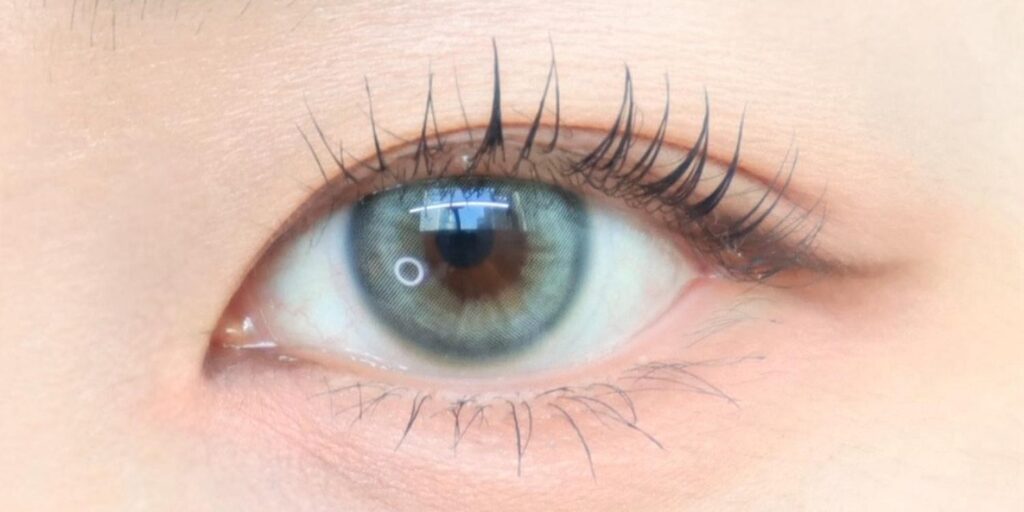 Uria Turkish Blue Cat Eye 6-month colored contacts on dark eyes showing soft sage-green with blue-gray undertone for natural seamless look
