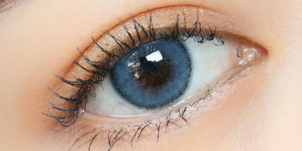 Kitty Kawaii Olivia Blue monthly colored contacts on dark eyes showing steel blue with fine halftone dot pattern and dark outer ring